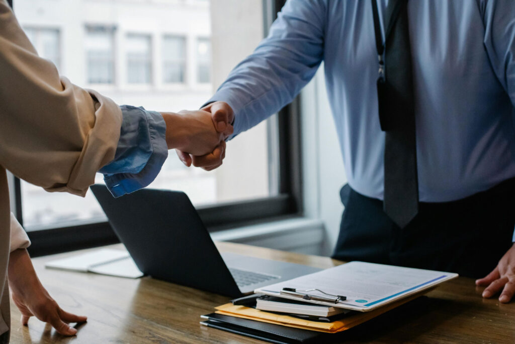 Two people shake hands in an office after signing documents